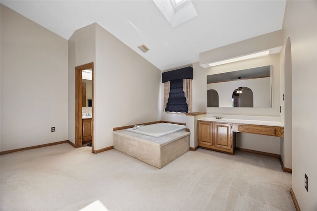 bathroom featuring vanity, baseboards, visible vents, lofted ceiling with skylight, and a bath