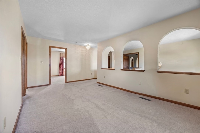 unfurnished room featuring baseboards, light colored carpet, and visible vents