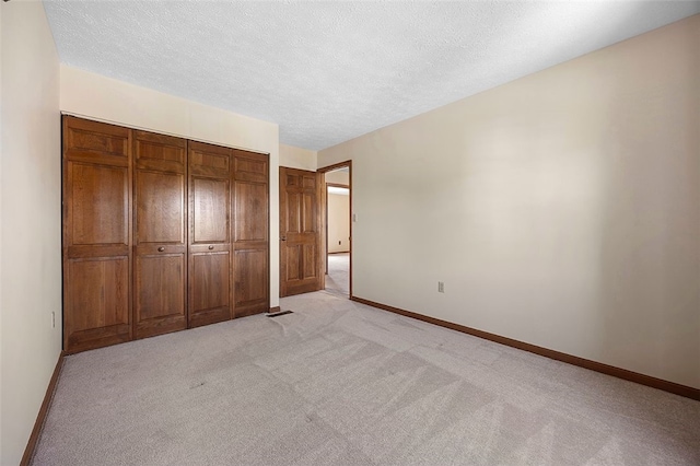 unfurnished bedroom with a textured ceiling, baseboards, light carpet, and a closet