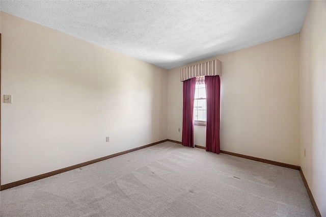 unfurnished room featuring a textured ceiling, light colored carpet, and baseboards