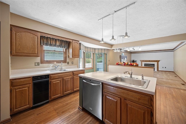 kitchen with a sink, track lighting, stainless steel dishwasher, and wood-type flooring