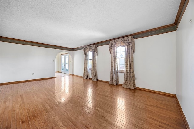 unfurnished room with crown molding, arched walkways, and a wealth of natural light