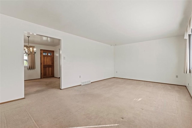 empty room with light colored carpet, baseboards, a notable chandelier, and visible vents