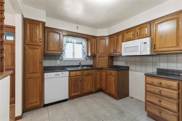 kitchen featuring a sink, backsplash, brown cabinets, and white appliances