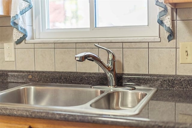 interior details with dark countertops, decorative backsplash, and a sink