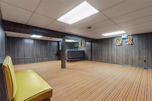 finished below grade area with carpet floors, wood walls, baseboards, and a drop ceiling