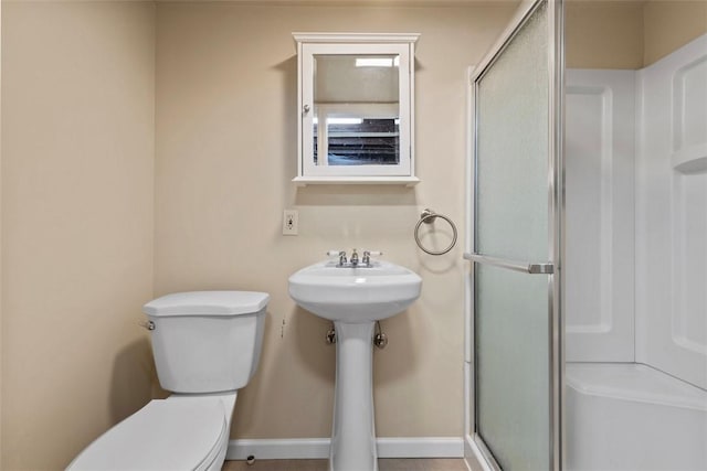 bathroom with an enclosed shower, baseboards, and toilet