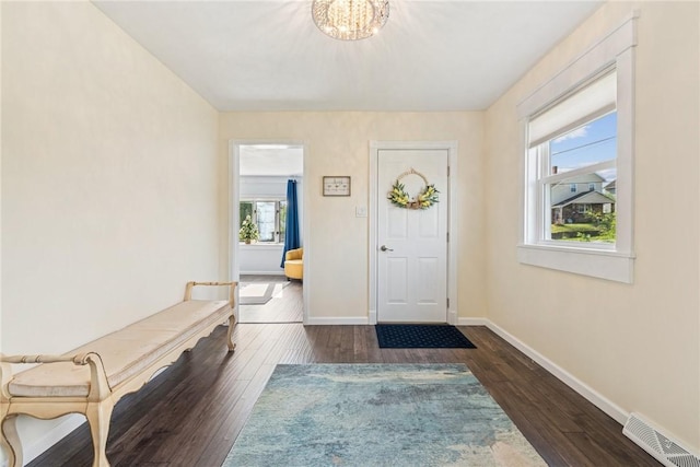 entryway featuring baseboards, dark wood-type flooring, a chandelier, and visible vents