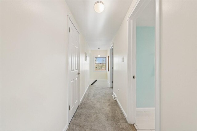 hall with light colored carpet and baseboards