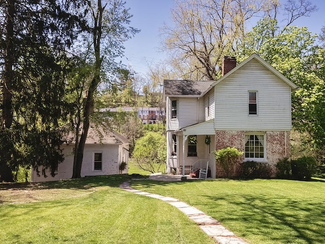 rear view of house with a lawn, a shingled roof, brick siding, and a chimney