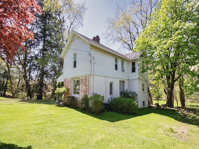 view of home's exterior with a lawn, brick siding, and a chimney