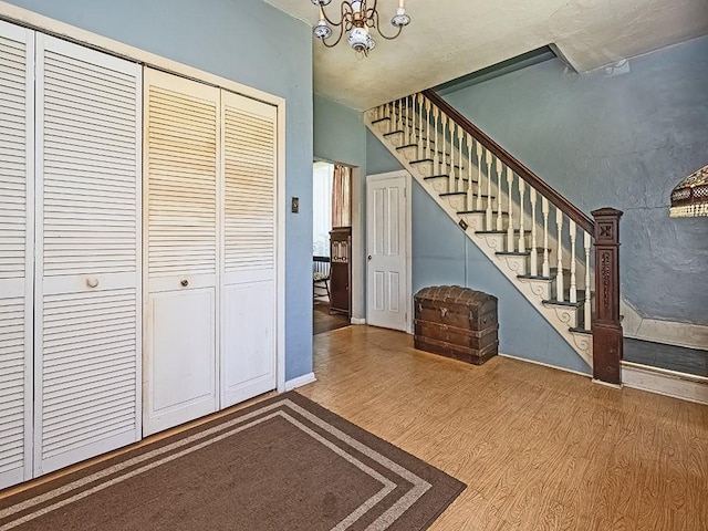 entryway with baseboards, wood finished floors, a notable chandelier, and stairway