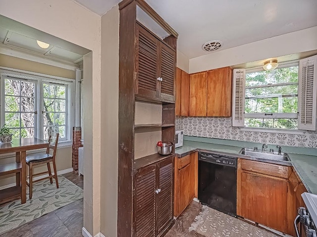 kitchen featuring range, brown cabinets, dishwasher, a sink, and baseboards