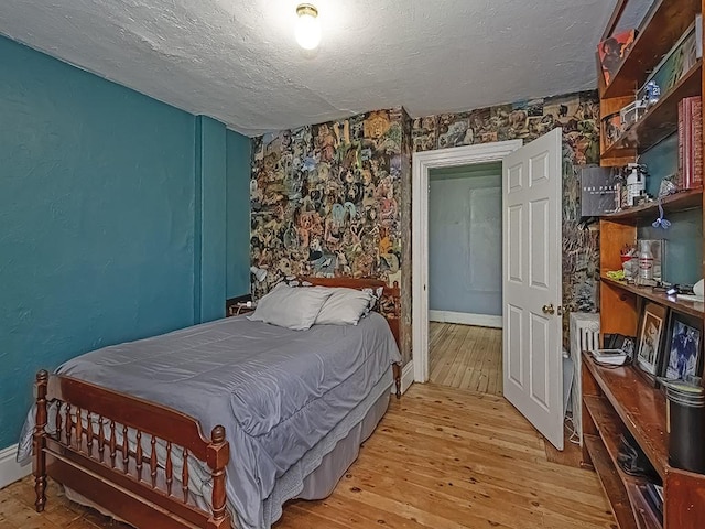 bedroom featuring baseboards, light wood-type flooring, and a textured ceiling