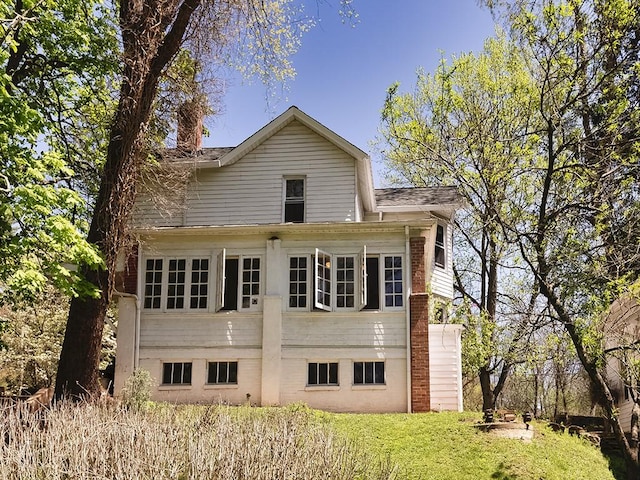 rear view of property with a yard, a chimney, and a shingled roof