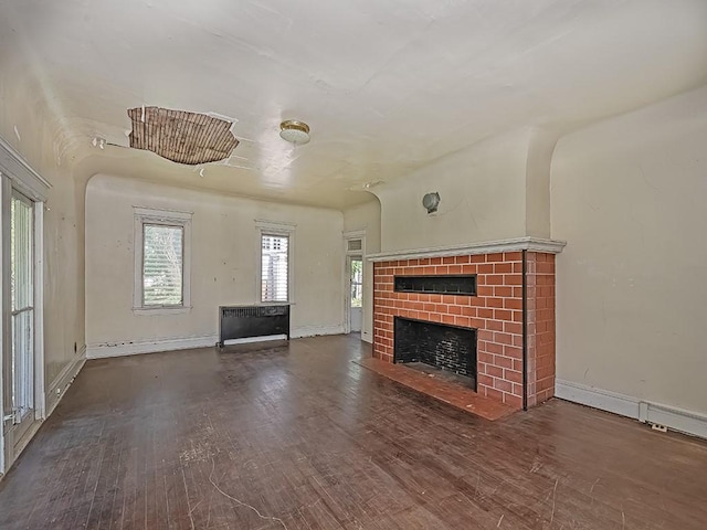 unfurnished living room with baseboards, wood finished floors, and a fireplace
