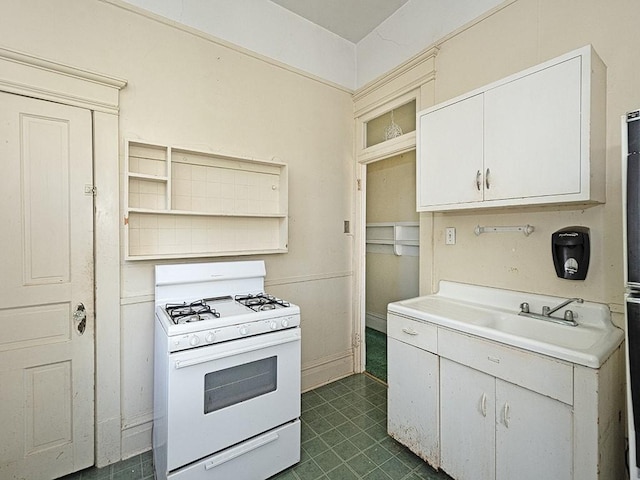 kitchen with white gas range, light countertops, open shelves, and a sink
