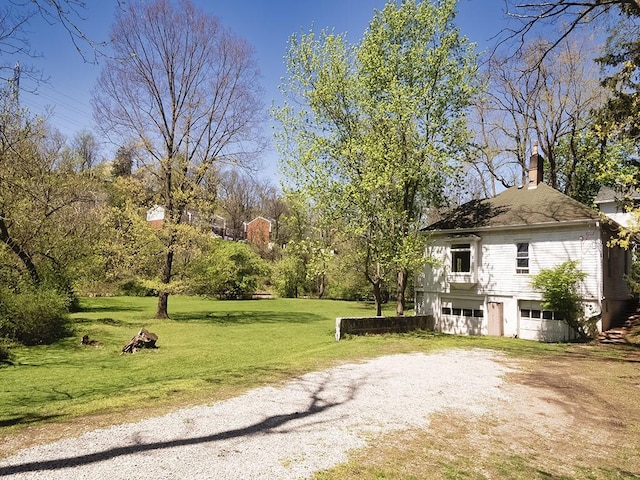 view of yard with dirt driveway and an attached garage