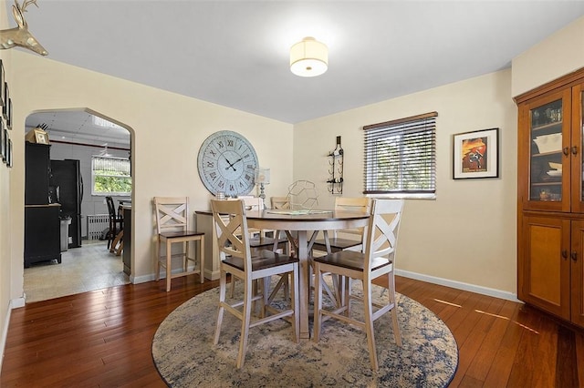 814 Clara St N, Versailles, PA 15137 - dining room featuring arched walkways, baseboards, hardwood / wood-style flooring, and radiator