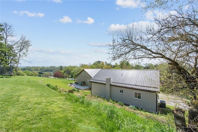 1460 Guffey Rd, North Huntingdon, PA 15642 - view of home's exterior with stucco siding, central AC unit, metal roof, a trampoline, and a yard