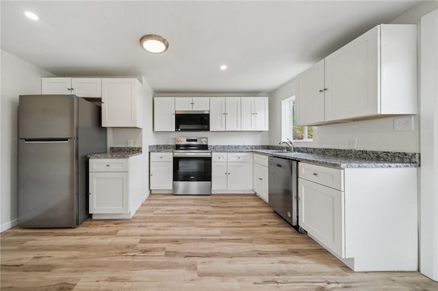 1460 Guffey Rd, North Huntingdon, PA 15642 - kitchen featuring light wood-type flooring, dark stone countertops, white cabinets, and stainless steel appliances
