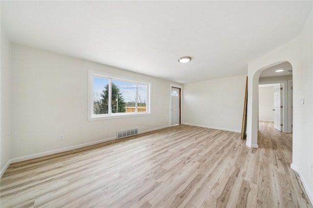 1460 Guffey Rd, North Huntingdon, PA 15642 - unfurnished living room featuring arched walkways, baseboards, visible vents, and light wood-type flooring