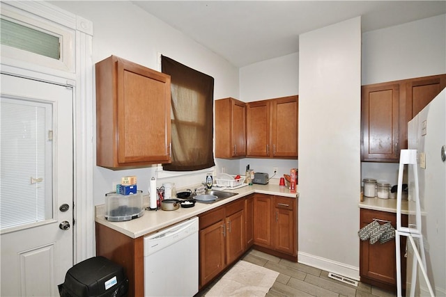 kitchen with visible vents, light countertops, brown cabinets, and white appliances