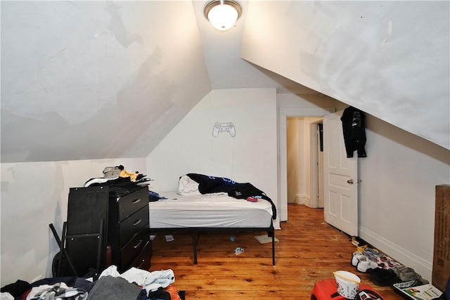 bedroom with vaulted ceiling and wood finished floors