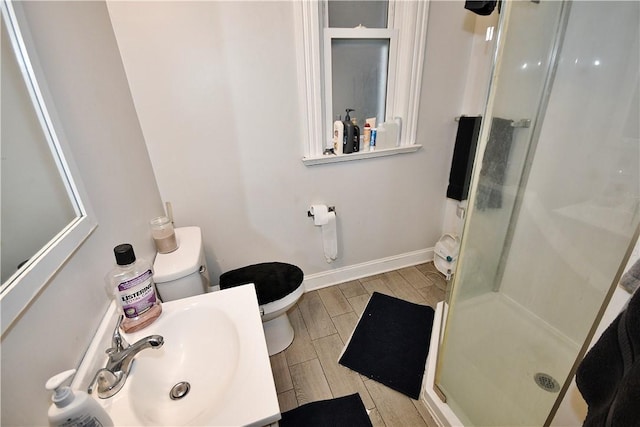 bathroom featuring baseboards, a sink, toilet, and a shower stall