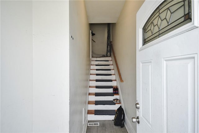 stairway with baseboards, wood finished floors, and visible vents