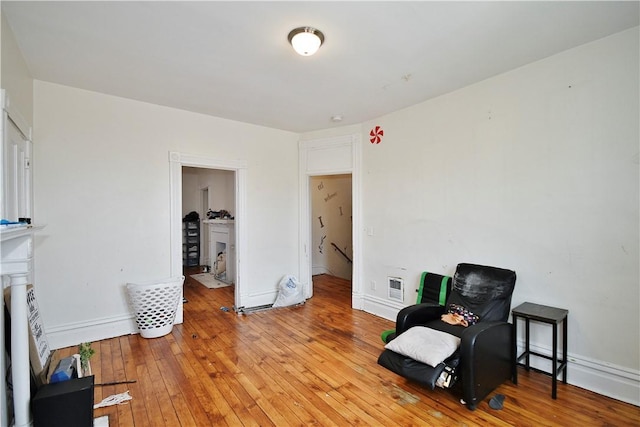 living area featuring light wood-style floors, heating unit, baseboards, and an upstairs landing
