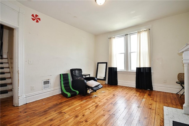 sitting room with baseboards, hardwood / wood-style flooring, stairs, and visible vents