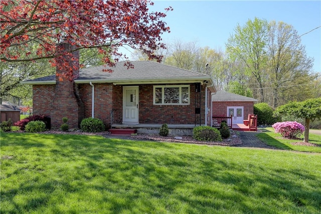 view of front of home with roof with shingles, a front lawn, and brick siding