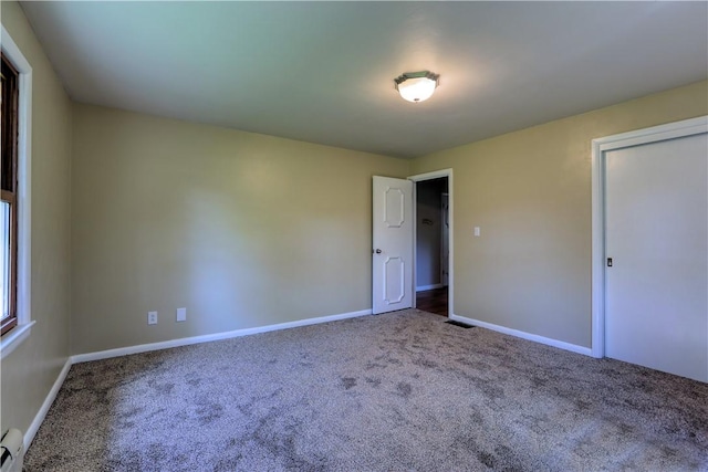 unfurnished bedroom with carpet floors, baseboards, and a baseboard radiator