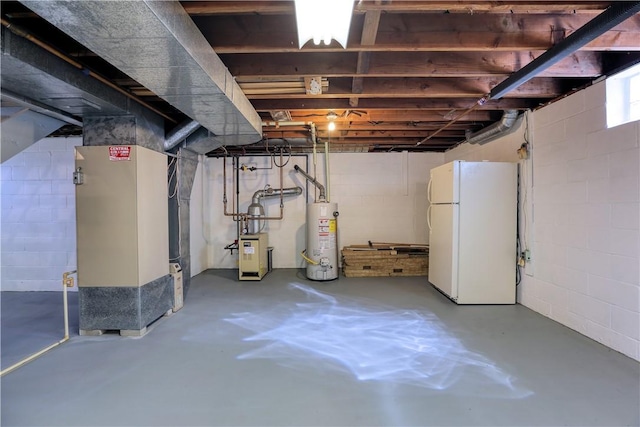 below grade area featuring freestanding refrigerator, concrete block wall, heating unit, and water heater