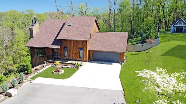 rustic home with an attached garage, a front lawn, board and batten siding, a chimney, and concrete driveway