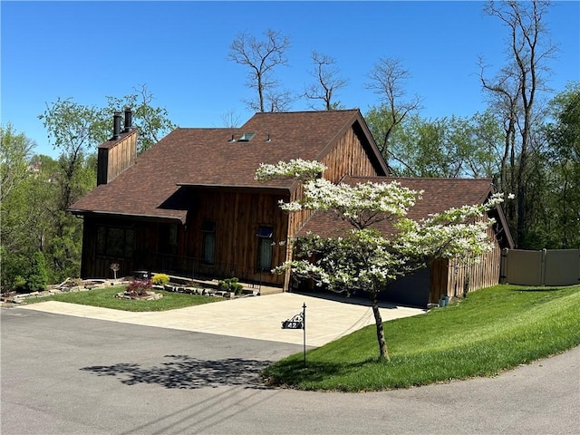view of front of home featuring a front lawn, a chimney, a shingled roof, board and batten siding, and concrete driveway