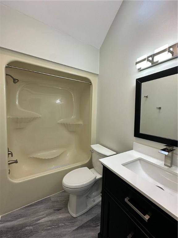 bathroom featuring tub / shower combination, vanity, toilet, and lofted ceiling