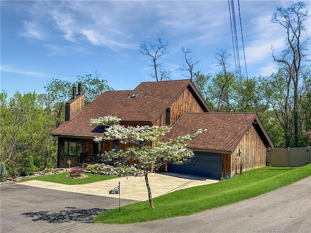 view of front of home with driveway, a chimney, a front yard, a garage, and fence