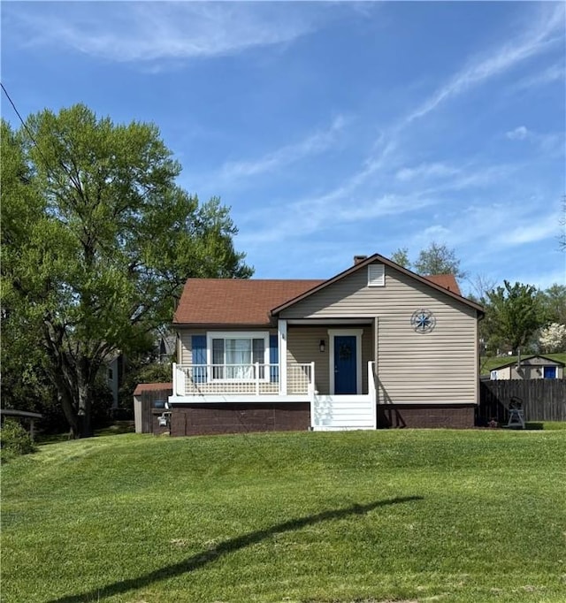 bungalow-style house featuring a front lawn, fence, and a wooden deck
