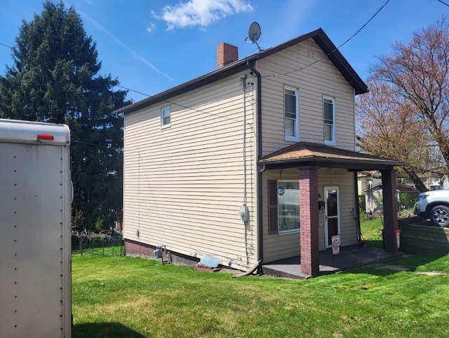 view of home's exterior with a lawn, a chimney, and a patio area