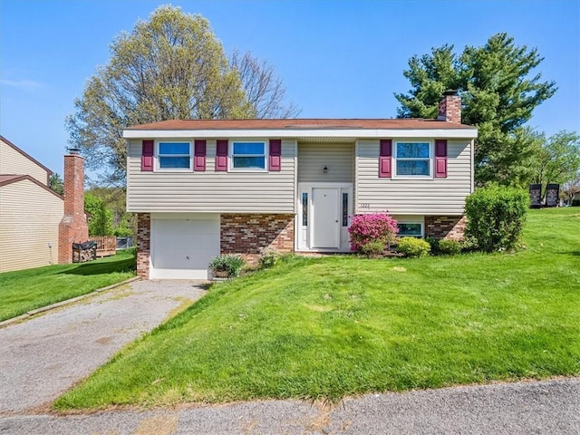 bi-level home featuring brick siding, a front lawn, an attached garage, and driveway