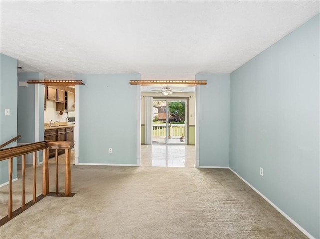 empty room featuring carpet floors, baseboards, and a sink