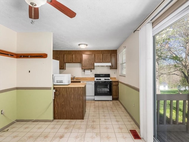 kitchen featuring white appliances, light floors, light countertops, under cabinet range hood, and a ceiling fan