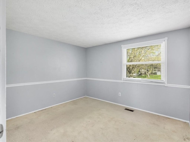 carpeted empty room featuring a textured ceiling, baseboards, and visible vents