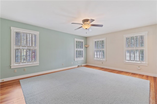 spare room featuring baseboards, a ceiling fan, wood finished floors, and visible vents