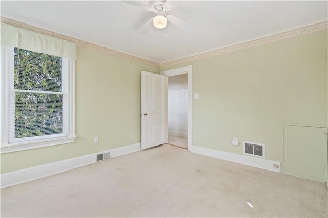 carpeted spare room with visible vents, a ceiling fan, baseboards, and ornamental molding