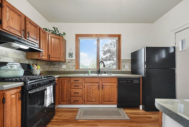 961 Deely St, Greenfield, PA 15217 - kitchen with brown cabinets, a sink, black appliances, light wood-style floors, and under cabinet range hood
