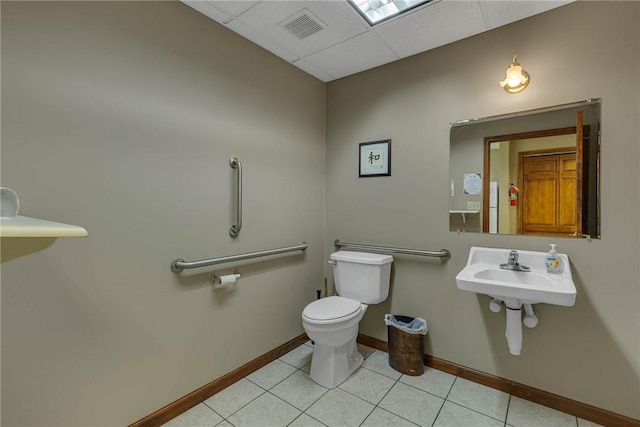 half bathroom with a sink, tile patterned flooring, toilet, baseboards, and visible vents
