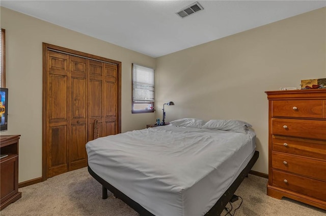 bedroom featuring baseboards, light colored carpet, visible vents, and a closet